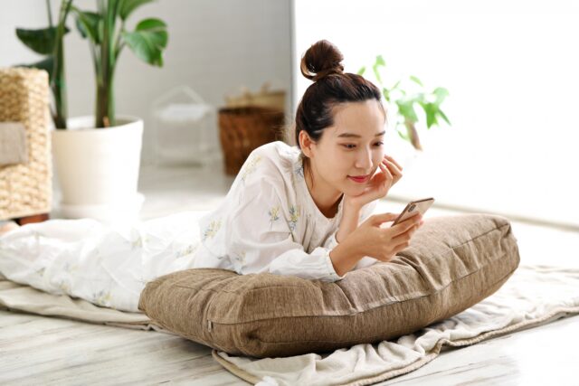 奄美ツアーズ　スマホで航空券を比較する女性
