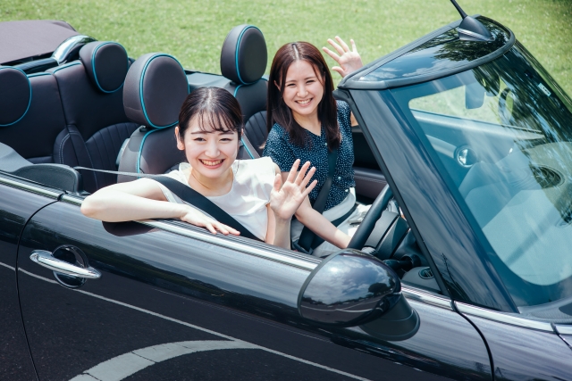 オープンカーから手を振る女性