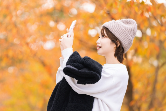 スマホで紅葉の写真を撮る女性